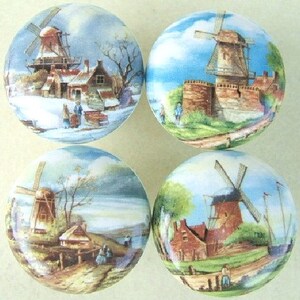 May include: Set of four ceramic cabinet knobs featuring a vintage illustration of a windmill in a rural landscape. Each knob has a different scene with a windmill, houses, trees, and a blue sky.