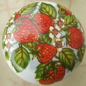 May include: A white ceramic knob with a colorful strawberry design. The knob features red strawberries, green leaves, and white flowers.