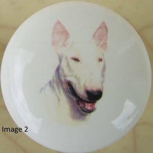 May include: A white Bull Terrier dog with pink ears, looking directly at the camera with its mouth open. The dog is depicted in a watercolor style on a white ceramic tile.
