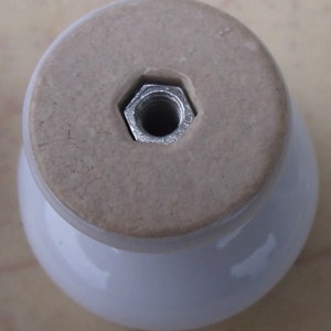 May include: White ceramic knob with a silver metal threaded insert. The knob has a smooth, rounded top and a slightly textured base.