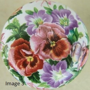 May include: A round, white decorative object featuring a floral design. The design includes red, purple, and pink pansies with green leaves. The text "Image 3" is visible at the bottom left.