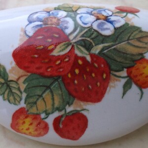 May include: White ceramic dish with a floral design featuring strawberries and flowers. The dish has a scalloped edge and is decorated with a hand-painted design.
