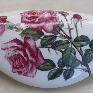 May include: White ceramic door knob with a floral design featuring pink roses and green leaves.