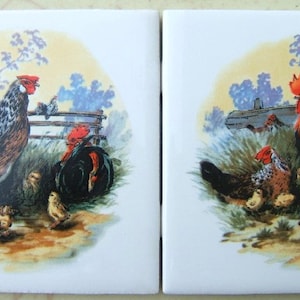 May include: Two ceramic tiles with a rooster and hen with chicks. The rooster is red and black with a red comb and wattles. The hen is brown and black with a red comb. The chicks are yellow. The tiles are white with a painted background of a farm scene.