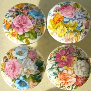 May include: Four round decorative cabinet knobs with floral designs. Each knob features a different arrangement of colorful flowers, including roses, in shades of pink, blue, orange, and yellow, set against a white background.