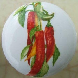 May include: A white ceramic knob with a colorful image of red and green chili peppers on a vine.