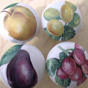 May include: Four ceramic knobs with painted fruit designs. The knobs feature a plum, grapes, a pear, and a cluster of green grapes.