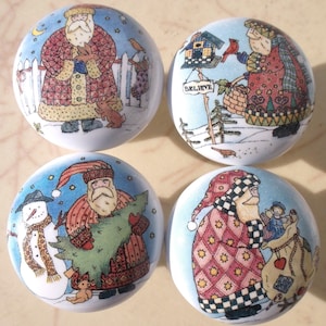 May include: Four round Christmas-themed decorative knobs. Each knob features a different illustration of Santa Claus in a winter scene. The illustrations include a snowman, a birdhouse, and a Christmas tree. The knobs have a glossy finish.