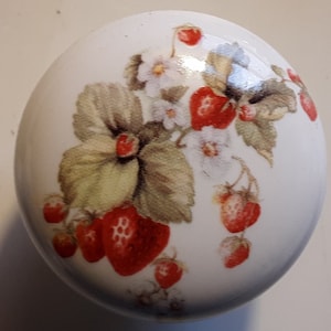 May include: White ceramic knob with a floral design featuring red strawberries and green leaves.