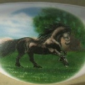 May include: A white ceramic oval dish with a painted image of a black horse running through a green field with a blue sky and white clouds in the background.