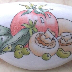 May include: White ceramic cabinet knob with a painted design of a red tomato, two mushrooms, green peas, and green pea pods.