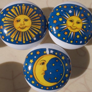 May include: Three ceramic knobs with a blue background and white stars. One knob features a yellow sun with a smiling face, another knob features a yellow moon with a smiling face, and the third knob features a yellow crescent moon with a smiling face.