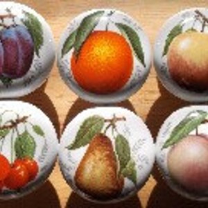 May include: Six ceramic knobs with painted fruit designs. The knobs feature plums, an orange, an apple, cherries, a pear, and a peach.