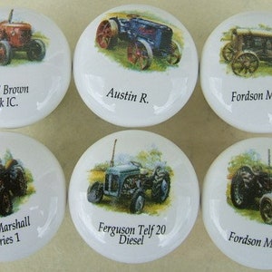 May include: Six white ceramic cabinet knobs with vintage tractor illustrations. Each knob features a different tractor model, including David Brown Vak IC, Austin R., Fordson Model "F", Field Marshall Series 1, Ferguson Telf 20 Diesel, and Fordson Model "N".