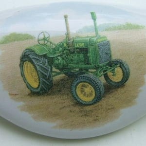 May include: A green and black John Deere tractor with a white background. The tractor is in a field with green grass and a blue sky.