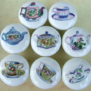 May include: Set of ten ceramic drawer knobs featuring vintage teacups and teapots. The knobs are white with colorful designs of teacups, teapots, and floral patterns.