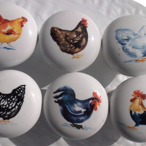 May include: Six white ceramic knobs with painted images of chickens and roosters. The knobs feature a variety of colors, including yellow, brown, blue, black, and white.