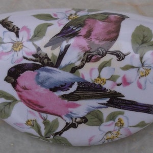 May include: White ceramic drawer pull with a floral design featuring two pink birds with blue wings and white flowers with yellow centers.