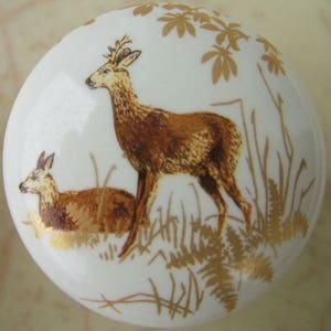 May include: White ceramic knob with a brown and gold design of two deer in a forest setting.