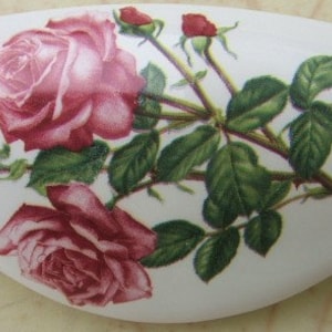 May include: A white ceramic oval dish with a floral design featuring pink roses and green leaves.