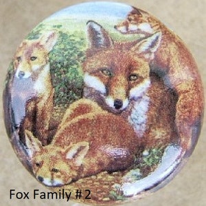 May include: A close-up of a painting of a fox family. The mother fox is in the center of the image, with two kits on either side of her. The mother fox is looking at the viewer, while the kits are looking down. The background is a blurry image of a forest.