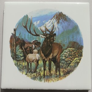 May include: Square ceramic tile featuring a detailed illustration of a herd of elk in a mountain landscape. The central elk is brown with large antlers, mouth open. The background includes mountains, trees, and a blue sky.