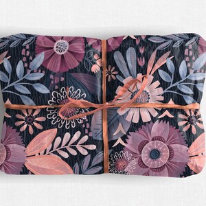 May include: A gift wrapped in floral patterned paper with a pink ribbon. The paper features a dark blue background with pink, peach, and white flowers and leaves.