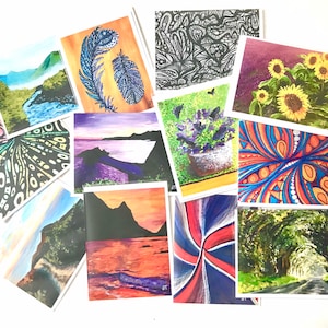 May include: A collection of 10 blank greeting cards with various colorful abstract and nature-inspired designs. The cards are all different sizes and shapes, and they are arranged in a random order. Some of the designs include a feather, a sunset, a sunflower, and a forest path.