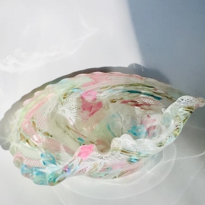 May include: A clear glass bowl with a scalloped edge and a swirl design in shades of pink, blue, and green.