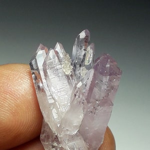 May include: A cluster of amethyst crystals with a purple hue and clear, faceted points. The crystals are arranged in a starburst pattern.