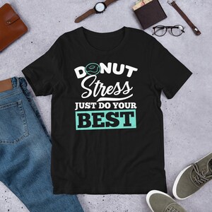 Puede incluir: Camiseta negra con un gráfico blanco que dice "Donut Stress Just Do Your Best" con un gráfico de donut sobre la palabra "Donut".