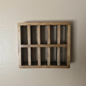 Puede incluir: Una estanter&iacute;a de pared de madera con 12 compartimentos rectangulares. La estanter&iacute;a est&aacute; te&ntilde;ida de un color marr&oacute;n oscuro.