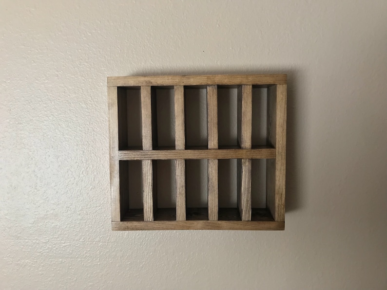 Puede incluir: Una estanter&iacute;a de pared de madera con 12 compartimentos rectangulares. La estanter&iacute;a est&aacute; te&ntilde;ida de un color marr&oacute;n oscuro.