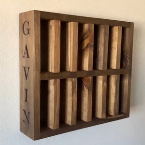 Puede incluir: Una estanter&iacute;a de pared de madera con el nombre "GAVIN" grabado en el lateral. La estanter&iacute;a tiene ocho compartimentos para guardar objetos peque&ntilde;os.