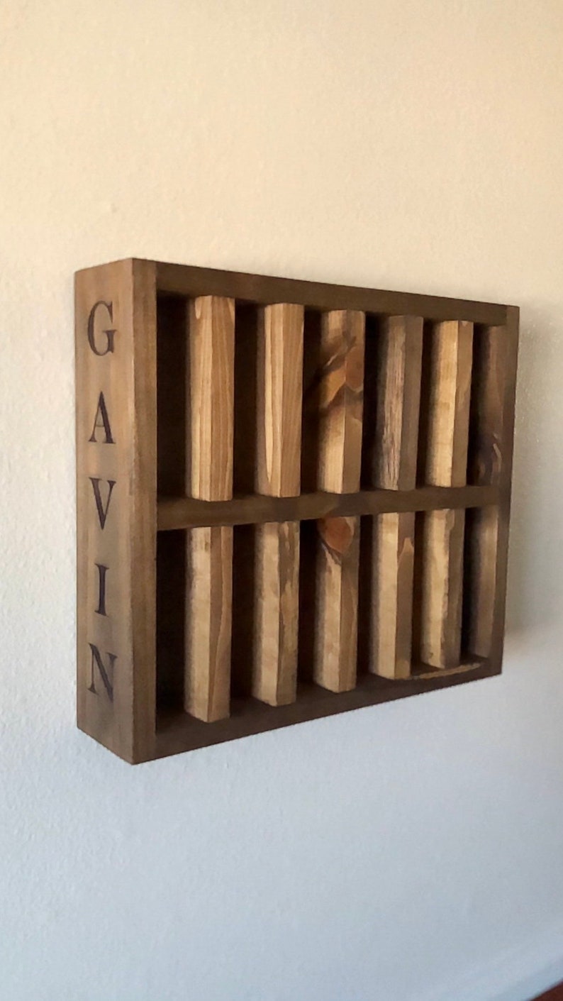 Puede incluir: Una estanter&iacute;a de pared de madera con el nombre "GAVIN" grabado en el lateral. La estanter&iacute;a tiene ocho compartimentos para guardar objetos peque&ntilde;os.