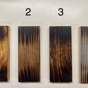 May include: Four wood samples with different levels of charring, labeled 1 through 4. The samples are arranged from lightest to darkest charring.