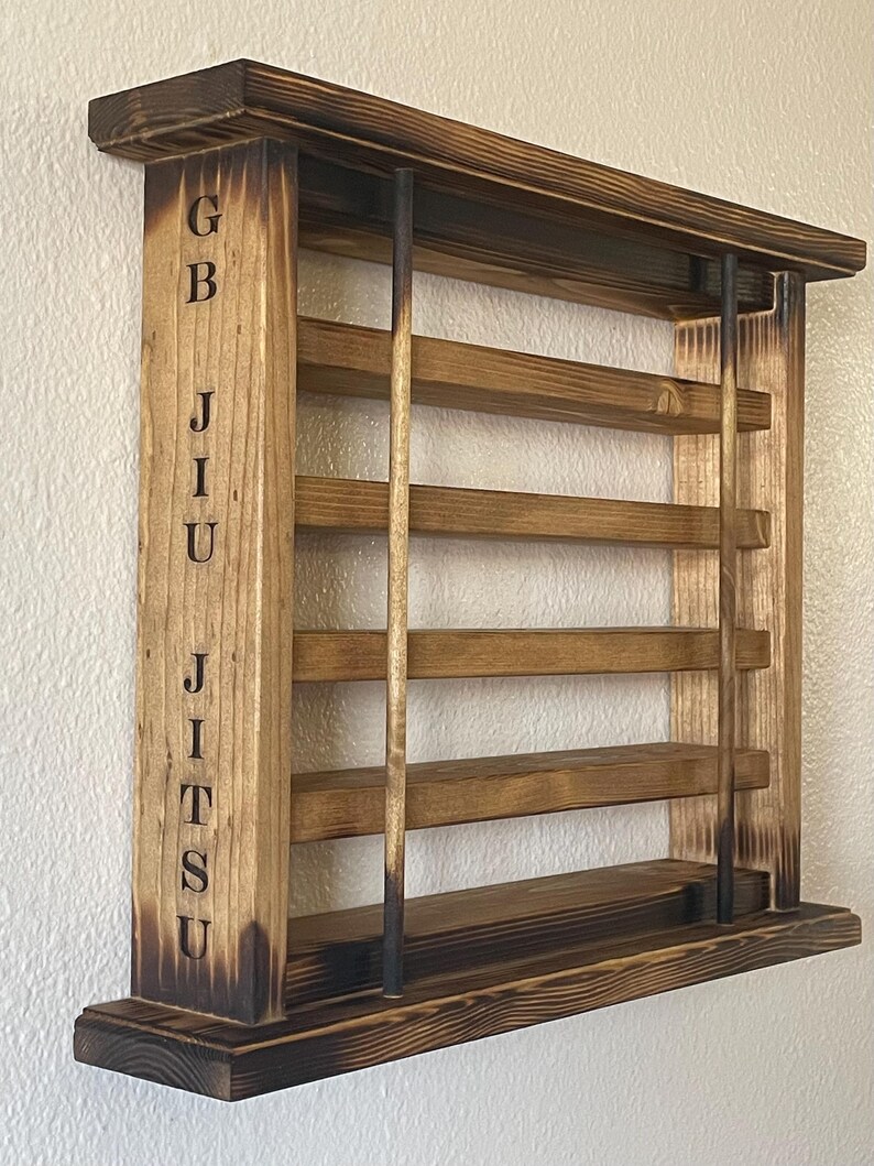 May include: A wooden wall-mounted shelf with a burnt finish. The shelf has five shelves and is labeled "GBJJU" on the side.