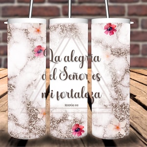 Peut inclure: Un gobelet blanc avec un motif marbré brun et blanc et des fleurs roses. Le gobelet porte une citation en espagnol qui dit "La alegria del Señor es mi fortaleza" avec la référence biblique "Nehemias 8:10".