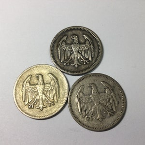 May include: Three silver coins with an eagle design. The eagle is facing forward with its wings spread out. The coins are slightly worn.