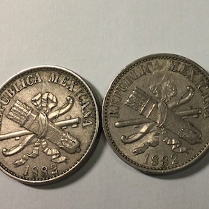 以下が含まれることがあります： 「REPUBLICA MEXICANA」と「1882」の刻印がされた、銀製のメキシコのコイン2枚。コインには、交差した矢と矢筒のデザインが施されています。