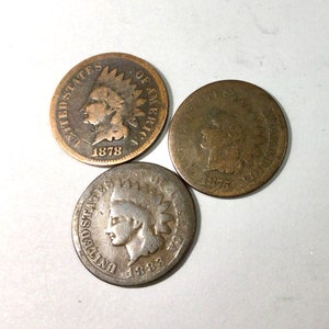 May include: Three copper US Indian Head pennies, one dated 1878, one dated 1875, and one dated 1883.