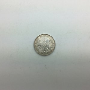 Puede incluir: Una moneda de plata con el n&uacute;mero "6" y el a&ntilde;o "1897" inscritos en ella.