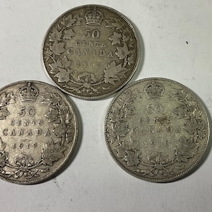 May include: Three silver-colored Canadian 50-cent coins from 1917, 1918, and 1919. Each coin features a central crown, the text 50 CENTS CANADA, and a wreath of maple leaves around the border. The coins are arranged in a triangular formation.