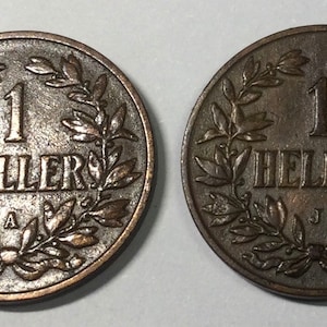 May include: Two sides of a copper coin with a wreath design and the text "1 HELLER" in the center.