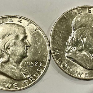 May include: Two silver-colored Franklin half-dollar coins featuring the profile of Benjamin Franklin. The left coin is dated 1952, and the right coin is dated 1949. Both coins display the text LIBERTY at the top and IN GOD WE TRUST at the bottom.