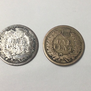 May include: Two copper US one cent coins, one with the Lincoln head side facing up and the other with the Lincoln Memorial side facing up.