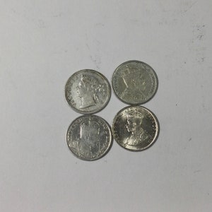 May include: Four silver coins featuring different portraits of monarchs. The coins are arranged in a square formation.