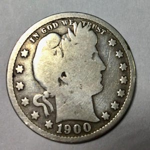 May include: A silver US quarter dollar coin with the profile of a man on one side and the words "In God We Trust" and "1900" on the other side.