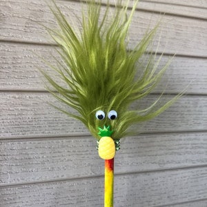 May include: A green fuzzy pencil with googly eyes, a green pineapple with a yellow top, and a rainbow-colored body.