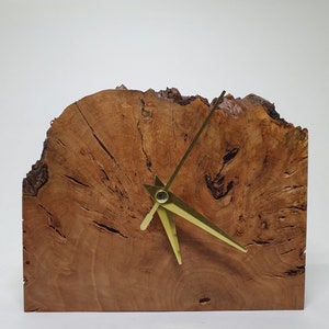 May include: A wooden clock with gold hands, the clock face is made from a slice of tree trunk with a natural wood grain pattern.